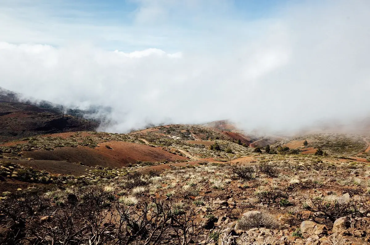 Low cloud rolling over red-brown volcanic hills with sparse scrub