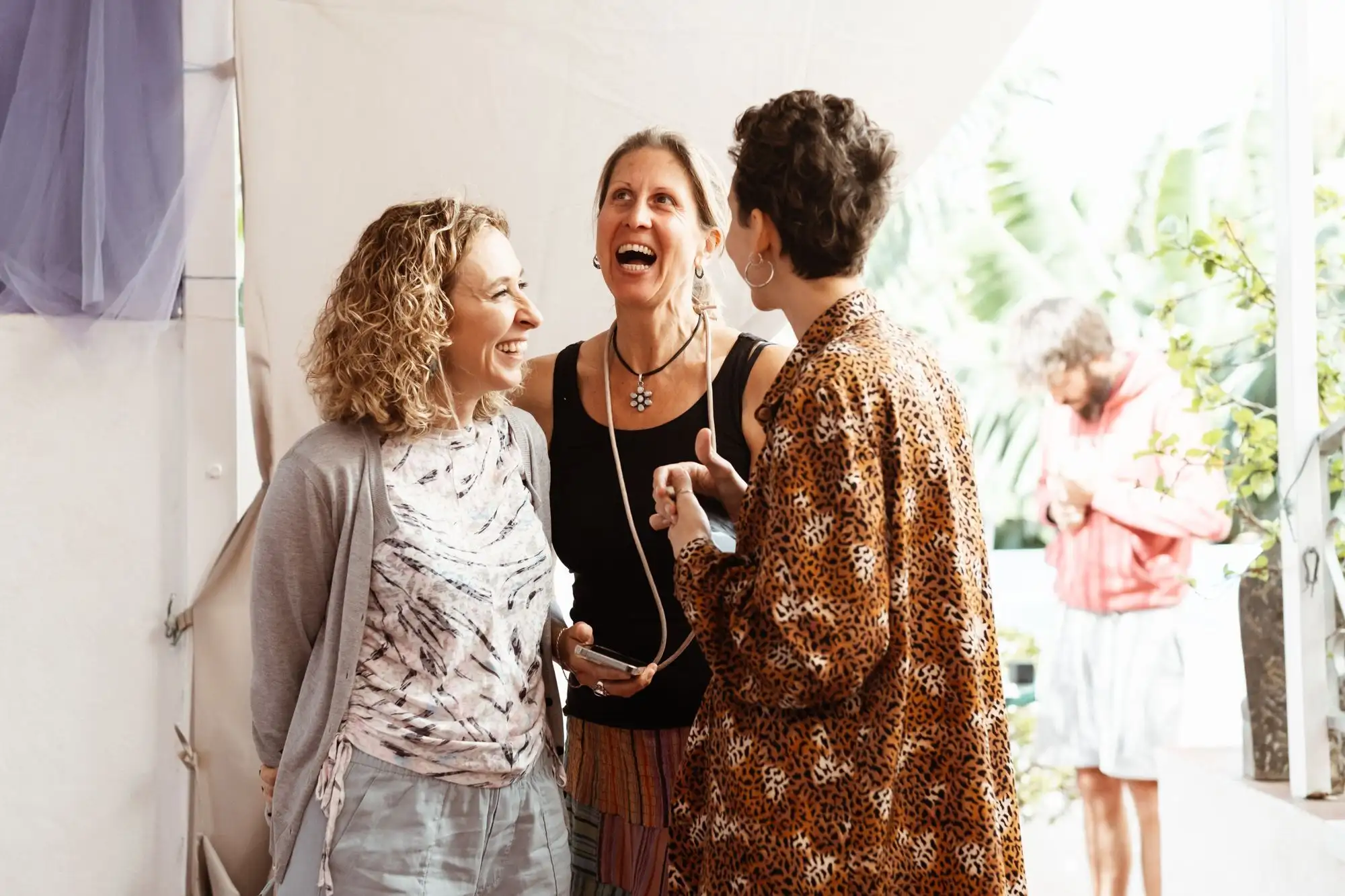 Three women laughing together in a doorway at a retreat venue